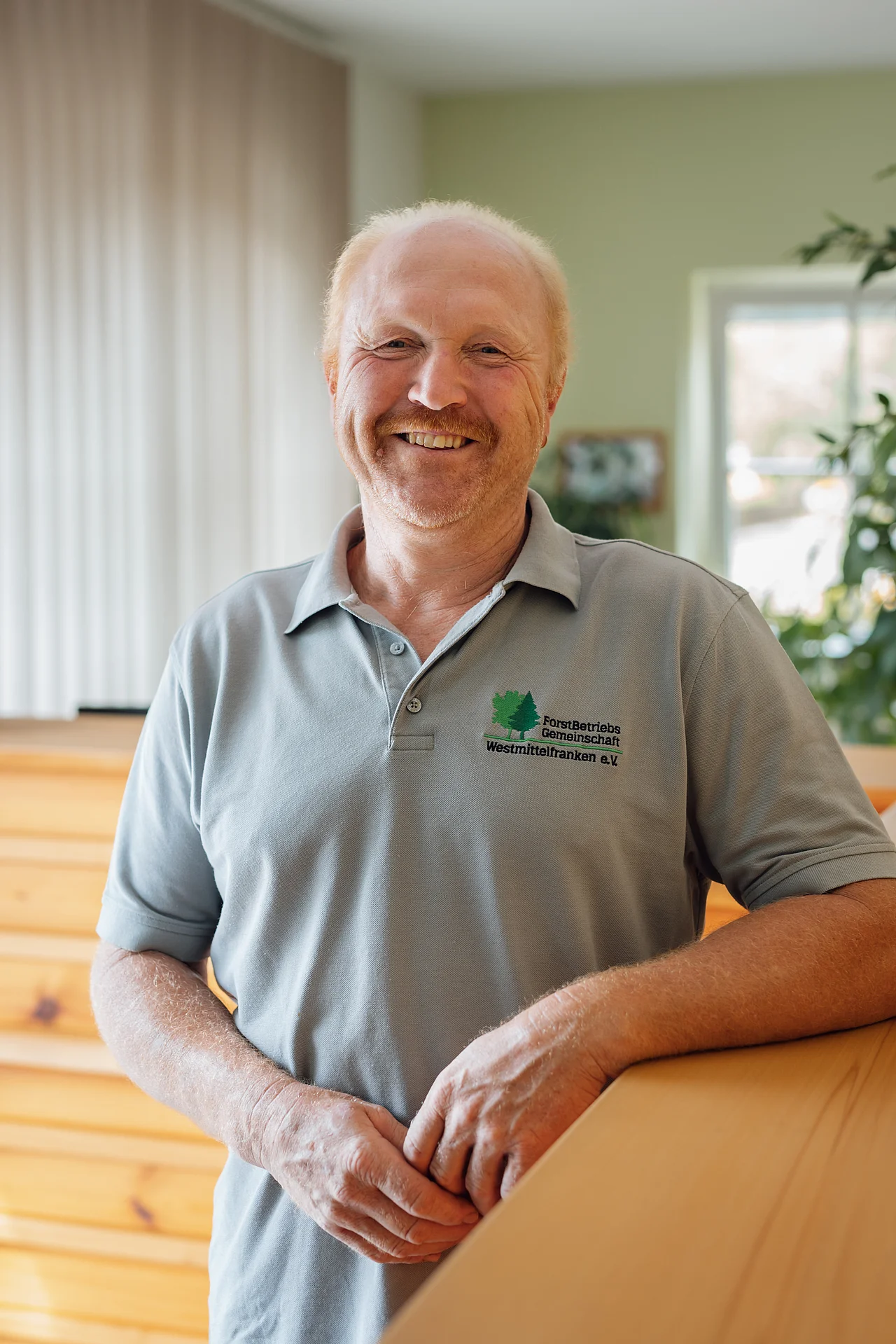 Werner Hager im grauen FBG-Poloshirt an einem Holztresen.